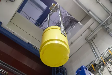 Ein Kran, der nach Atomgesetz zertifiziert ist, rangiert den Behälter durch die Deckenluke in die Reaktorhalle ins Obergeschoss. © Bernhard Ludewig, FRM II / TUM